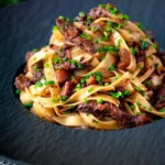 Beef cheek ragu served with pappardelle pasta and snipped chives.