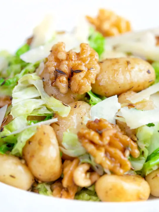 Close up cabbage and walnut gnocchi served with parmesan shavings.