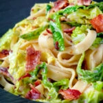 Close up creamy savoy cabbage pasta with crispy bacon and sour cream.