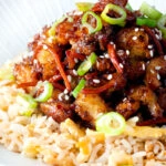 Close up Chinese takeaway style crispy orange chicken with egg fried rice.