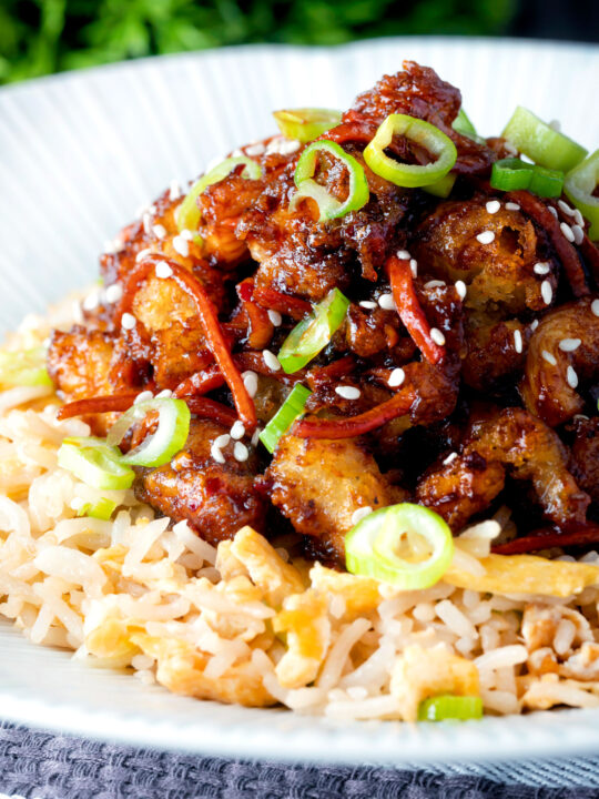 Close up Chinese takeaway style crispy orange chicken with egg fried rice.