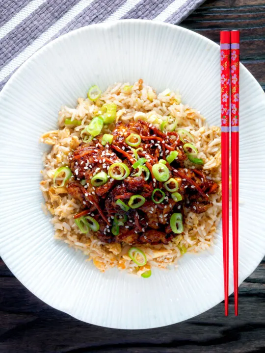 Overhead Chinese takeaway style crispy orange chicken with egg fried rice.