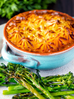 Individual traditional British mince beef cottage pie served in a blue earthenware bowl.