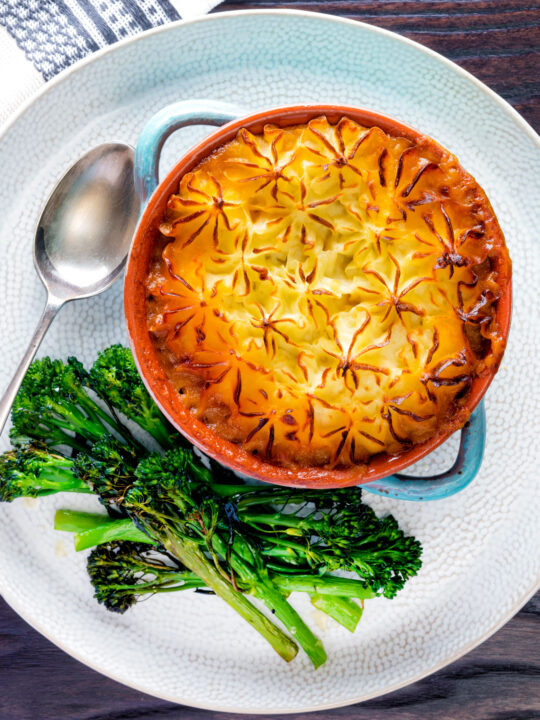 Overhead traditional British mince beef cottage pie served in a blue earthenware bowl.