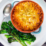 Overhead traditional British mince beef cottage pie served in a blue earthenware bowl featuring a title overlay.