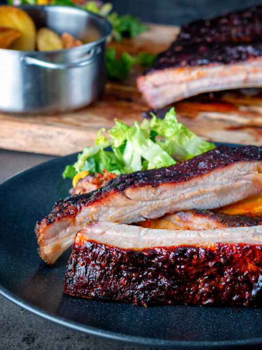 Oven baked sticky barbecue pork ribs served with salad and wedges.