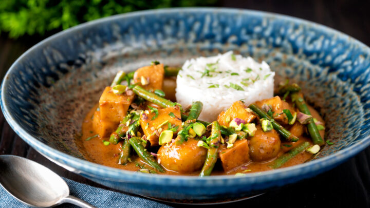 Vegan Thai massaman curry with potatoes, green beans, pistachio nuts and rice.