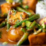 Close up vegan Thai massaman curry with potatoes, green beans and pistachio nuts.