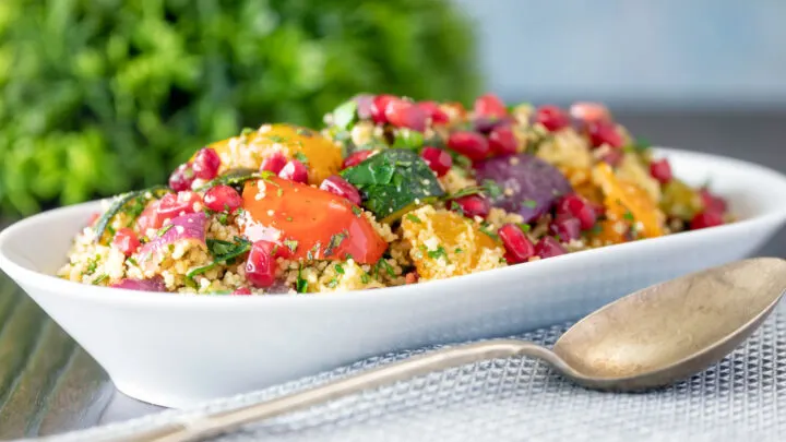 Vegetarian roasted vegetable couscous salad with fresh herbs and pomegranate arils.