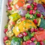 Close up vegetarian roasted vegetable couscous salad with pomegranate arils.