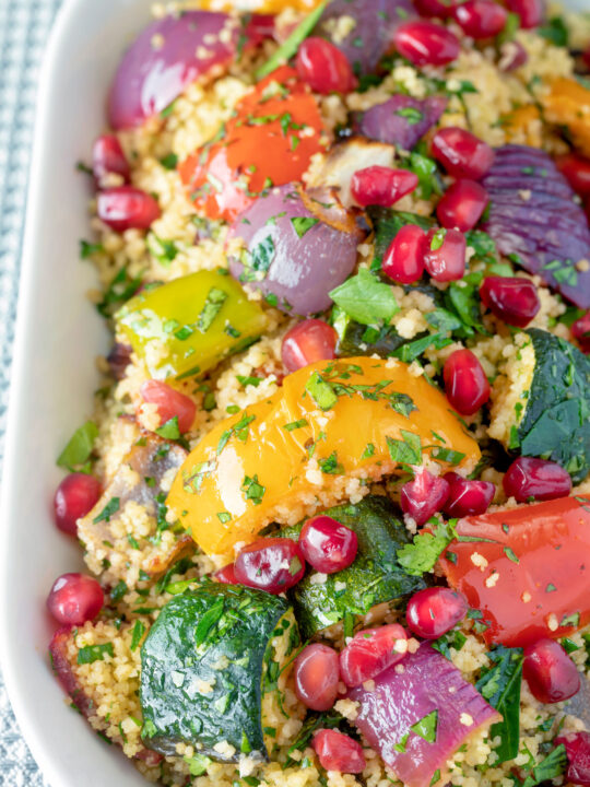 Close up vegetarian roasted vegetable couscous salad with pomegranate arils.