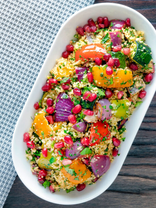 Overhead vegetarian roasted vegetable couscous salad with pomegranate arils.