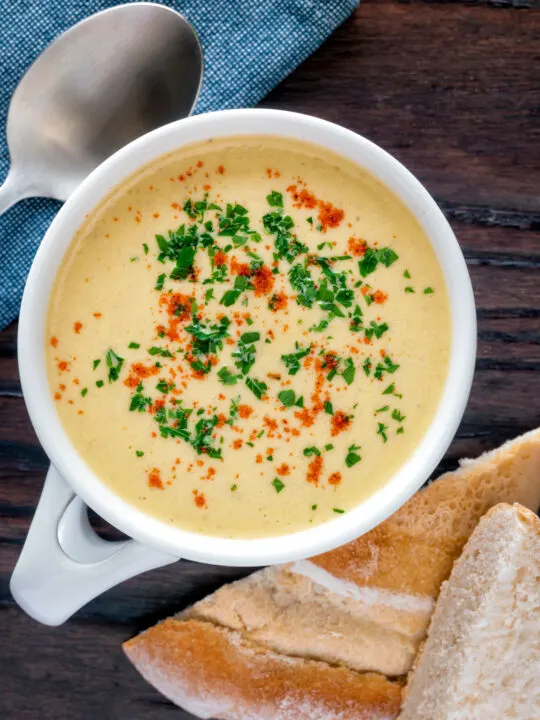 Overhead cream of celeriac soup served in a cup with bread.