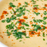 Close up cream of celeriac soup garnished with parsley and smoked paprika.