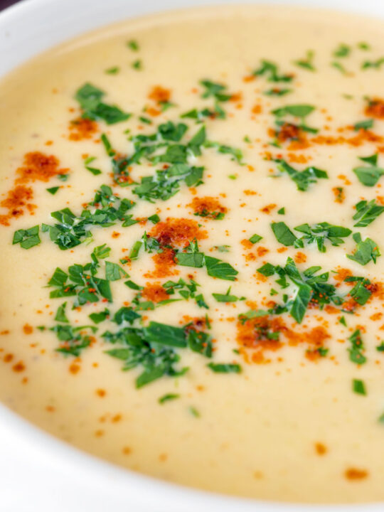 Close up cream of celeriac soup garnished with parsley and smoked paprika.