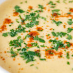 Close up cream of celeriac soup garnished with parsley and smoked paprika featuring a title overlay.