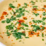 Close up cream of celeriac soup garnished with parsley and smoked paprika featuring a title overlay.