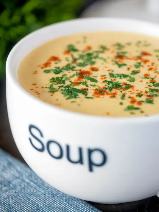 Cream of celeriac soup served in a cup garnished with parsley and paprika.