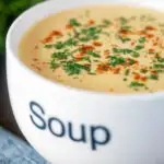 Cream of celeriac soup served in a cup garnished with parsley and paprika.