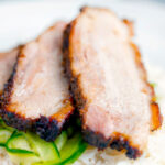 Sliced crispy Chinese Pork Belly served with rice and pickled cucumbers.