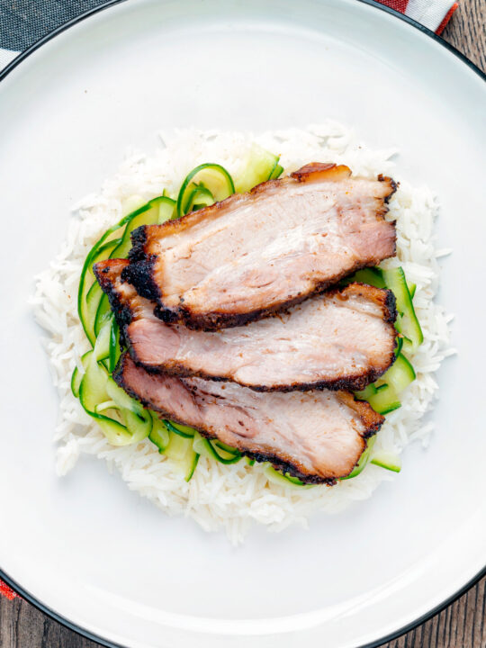 Overhead sliced crispy Chinese Pork Belly served with rice and pickled cucumbers.