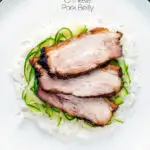 Overhead sliced crispy Chinese Pork Belly served with rice and pickled cucumbers featuring a title overlay.