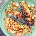 Overhead devilled mackerel fillets served with a pickled onion and tomato salad.
