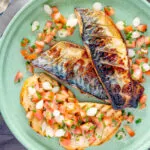 Overhead devilled mackerel fillets served with a pickled onion and tomato salad.