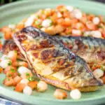 Devilled mackerel fillets served with a pickled onion and tomato salad featuring a title overlay.