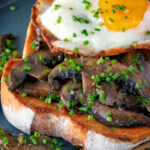 Close up devilled mushrooms on toast with a fried egg featuring a title overlay.