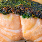 Close up baked pistachio nut and herb crusted salmon fillet.