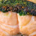 Close up baked pistachio nut and herb crusted salmon fillet featuring a title overlay.