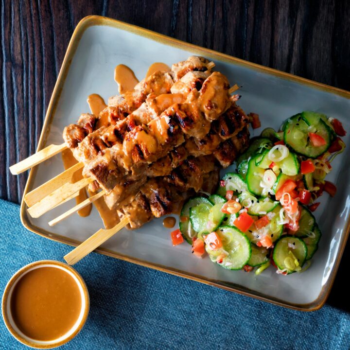 Pork satay skewers with peanut dipping sauce and cucumber salad.