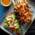 Overhead pork satay skewers with peanut dipping sauce.