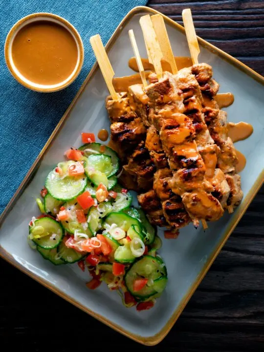 Overhead pork satay skewers with peanut dipping sauce.