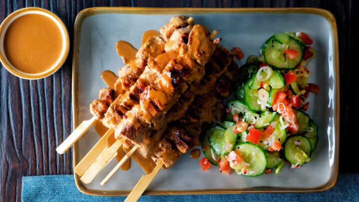 Pork satay skewers with peanut dipping sauce and cucumber salad.