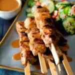 Pork satay skewers with peanut dipping sauce featuring a title overlay.