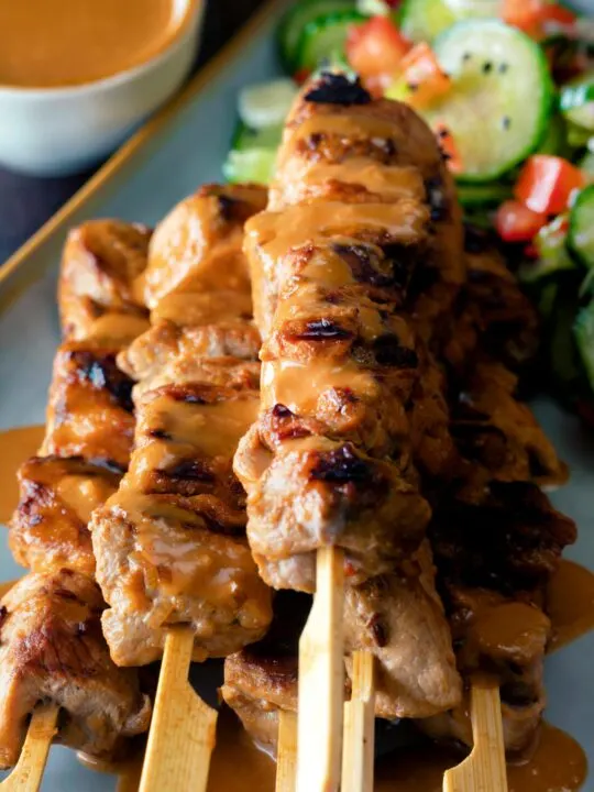 Close up pork satay skewers with peanut dipping sauce.
