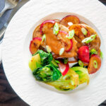 Overhead pork tenderloin with plum sauce, fresh plums and pak choi.