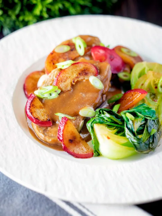 Pork tenderloin with plum sauce, fresh plums and pak choi.