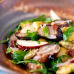 Sausage salad with apple, new potatoes, bacon and rocket or arugula.