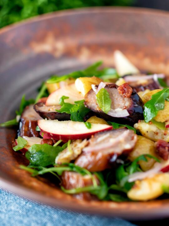 Sausage salad with apple, new potatoes, bacon and rocket or arugula.