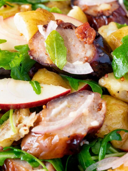 Close up sausage salad with apple, new potatoes, bacon and rocket or arugula.