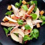 Overhead smoked mackerel salad with apple, bacon and croutons.