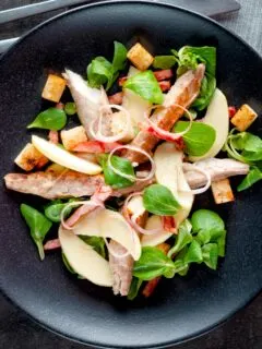 Overhead smoked mackerel salad with apple, bacon and croutons.
