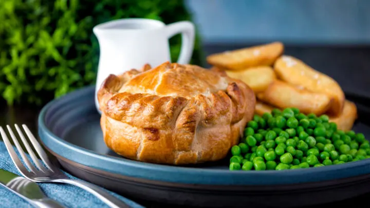 Hand raised steak and ale pie served with chips and peas and a jug of gravy.