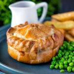 Hand raised steak and ale pie with chips and peas.