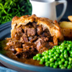 Hand raised steak and ale pie cut open to show filling served with chips and peas featuring a title overlay.