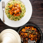 Overhead sweet potato tagine with dates and almonds served with buttered couscous.