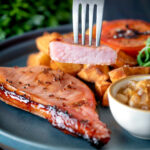 Cider glazed cut open bacon chops with fried potatoes, grilled tomato, rocket and apple chutney.